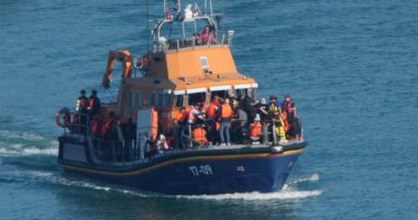 Migrants entering the water from a small boat.