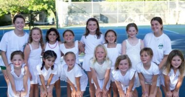 Group of girls in white dresses posing for a photo.