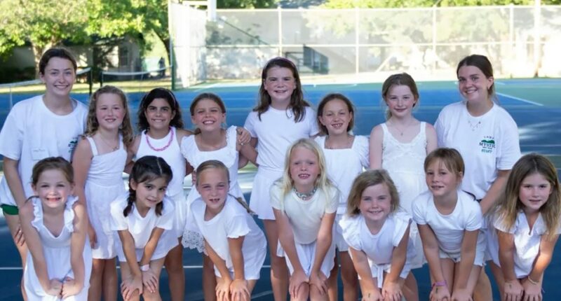 Group of girls in white dresses posing for a photo.