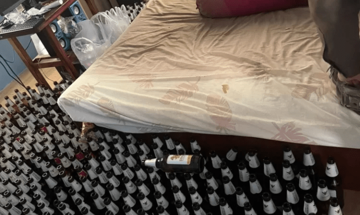 Many empty beer bottles surrounding a bed.