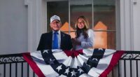 Donald and Melania Trump on a White House balcony with an American flag.