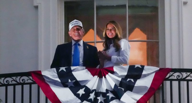 Donald and Melania Trump on a White House balcony with an American flag.