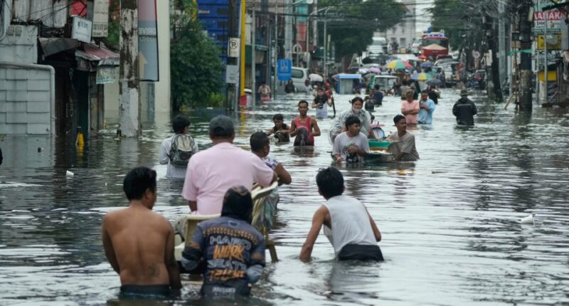 Residents wade through a flooded street in Malabon City, Philippines.