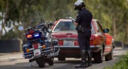 Motorcycle police officer writing a traffic ticket.
