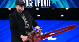Man in a black jacket holding a red chainsaw.