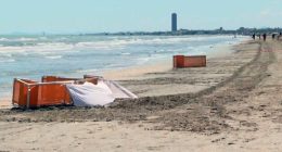 Beach scene with orange barriers and a white sheet near the water.