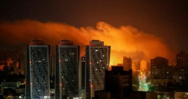 Nighttime view of a city skyline illuminated by an explosion.