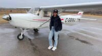 Woman standing in front of a small airplane.