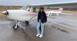 Woman standing in front of a small airplane.