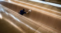 A worker cleaning the hull of a large yacht.