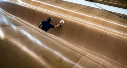 A worker cleaning the hull of a large yacht.