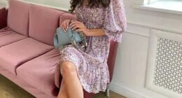 Woman in floral dress sitting on a pink couch.