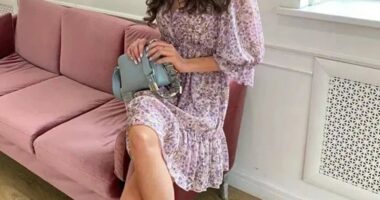 Woman in floral dress sitting on a pink couch.