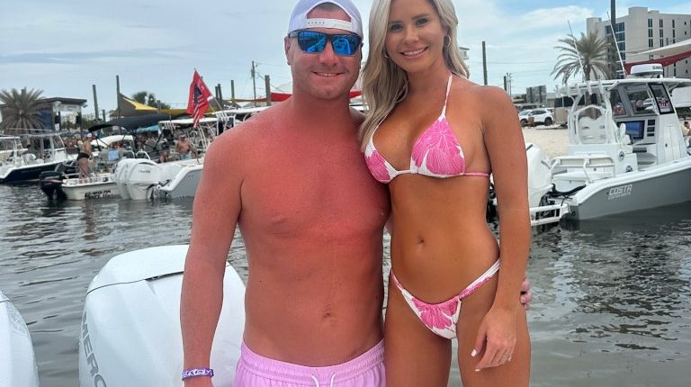 Couple in swimwear posing on a boat.