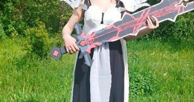 Woman in cosplay holding a large sword.