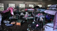 Muddy bunk beds and belongings in a flood-damaged cabin.