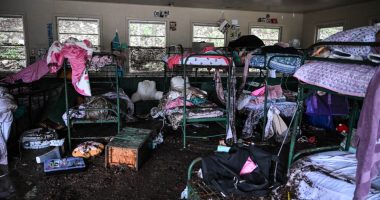 Muddy bunk beds and belongings in a flood-damaged cabin.