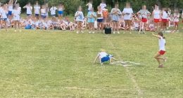 A girl falling during a field day event while other girls watch.