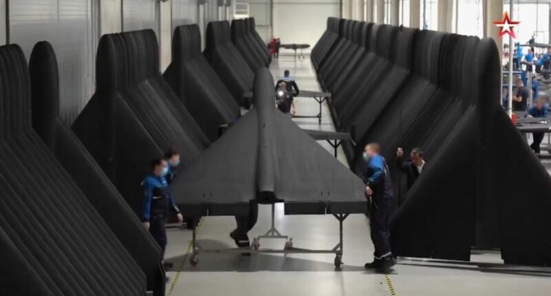 Person inspecting a large, dark-colored aircraft wing.