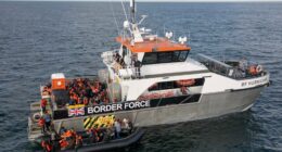 A Border Force vessel rescuing migrants from a small inflatable boat.