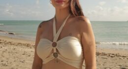 Woman on a beach in a beige halter top and matching skirt.