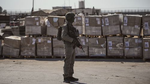 FILE - An Israeli soldier stands beside humanitarian aid packages awaiting pickup on the Palestinian side of the Kerem Shalom crossing in the Gaza Strip, Thursday, July 24, 2025, during a media tour organized by the Israeli army. (AP Photo/Ohad Zwigenberg, file)