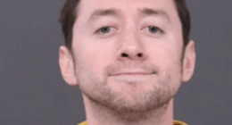 Mugshot of a man in a yellow shirt.