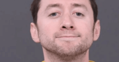 Mugshot of a man in a yellow shirt.