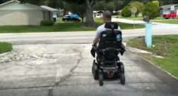 A man in a wheelchair on a damaged driveway.
