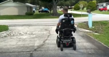 A man in a wheelchair on a damaged driveway.