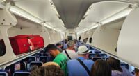 Passengers standing in an airplane aisle.