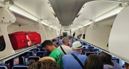 Passengers standing in an airplane aisle.