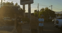 Police officer speaking with two men outside a Safeway.