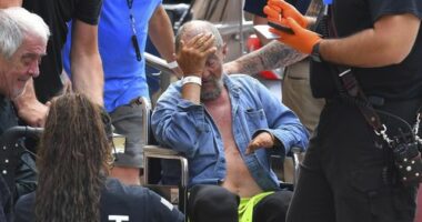 Michael Pimentel, center, a resident at the Gabriel House assisted living facility, in Fall River, Mass., receives assistance from an emergency medical worker, right, outside a temporary shelter, Monday, July 14, 2025, in Fall River, following a fire that started late Sunday. (AP Photo/Steven Senne)