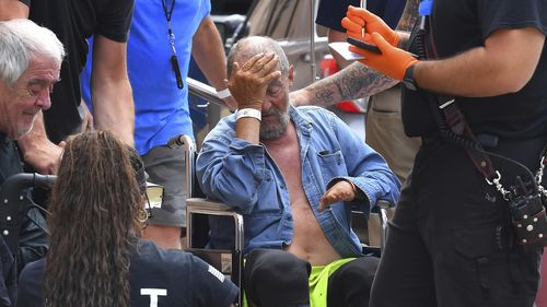 Michael Pimentel, center, a resident at the Gabriel House assisted living facility, in Fall River, Mass., receives assistance from an emergency medical worker, right, outside a temporary shelter, Monday, July 14, 2025, in Fall River, following a fire that started late Sunday. (AP Photo/Steven Senne)