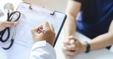 Close-up of a male doctor hand hold a silver pen and showing pad in hospital. Doctor giving prescription to the patient and filling up medical form at a clipboard
