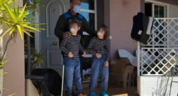 Police officer with two children outside a house.