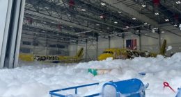 Two Spirit Airlines planes covered in foam inside a hangar.