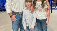 Family portrait of two adults and two children in cowboy hats and jeans.