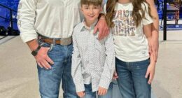 Family portrait of two adults and two children in cowboy hats and jeans.