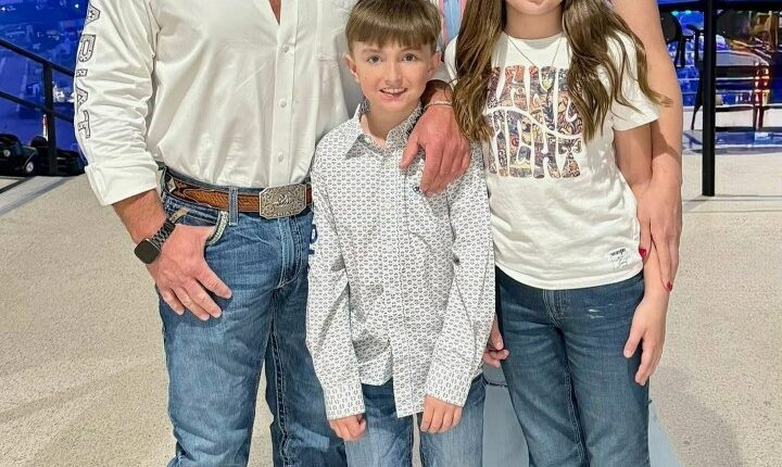 Family portrait of two adults and two children in cowboy hats and jeans.