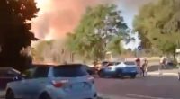 Large plume of smoke billowing near parked cars.