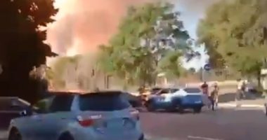 Large plume of smoke billowing near parked cars.