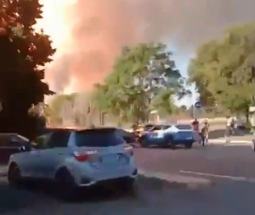 Large plume of smoke billowing near parked cars.
