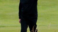 Donald Trump waving on a golf course.