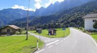Sagron Mis, Italy: A road curves through a village nestled in a mountain valley.