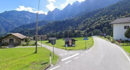 Sagron Mis, Italy: A road curves through a village nestled in a mountain valley.