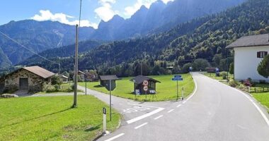 Sagron Mis, Italy: A road curves through a village nestled in a mountain valley.