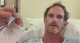 Man in hospital bed with bandaged hand.