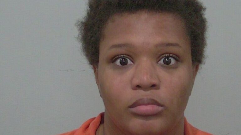 Mugshot of a young woman in an orange jumpsuit.